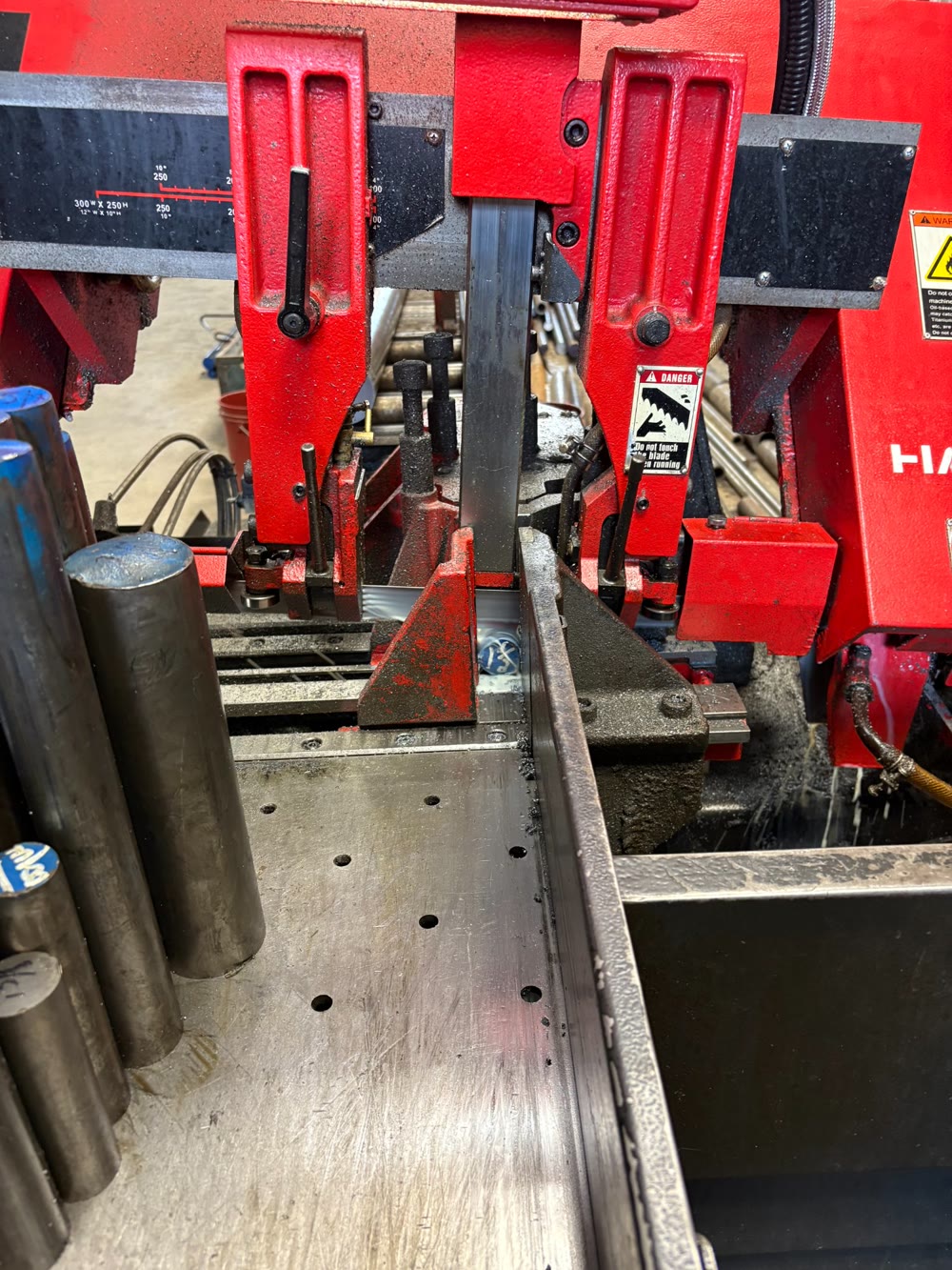 Band saw cutting steel bar stock at RPM Machining